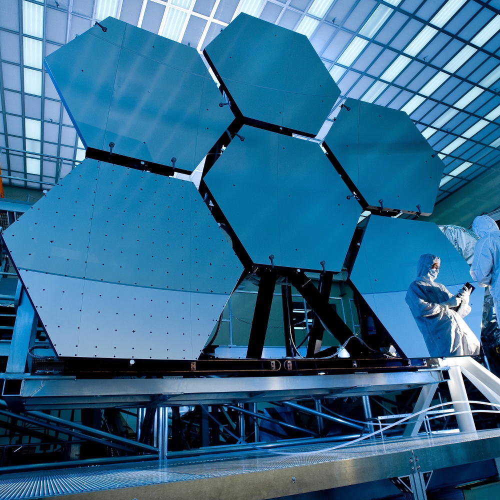 led-semiconductor-fab-cleanroom-lighting.png 半導體無塵室內部作業景象,工程人員穿著無塵衣在大型設備旁檢測,天花板以 LED 格柵燈與線性燈均勻照明,空間明亮低眩光。