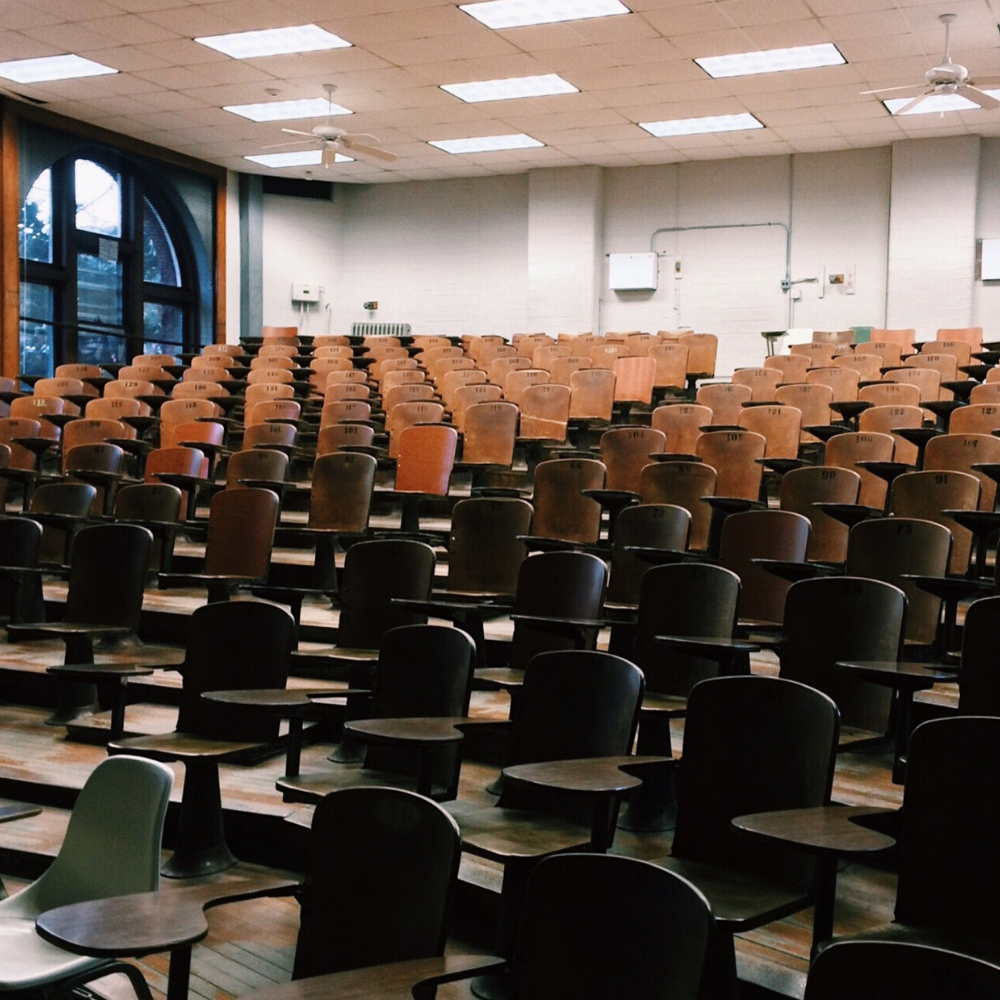led-school-lecture-hall-classroom-lighting.png 階梯式大教室,成排木質座椅與書寫桌,天花板配置 LED 平板燈與循環扇,光線均勻明亮,適合授課與考試。